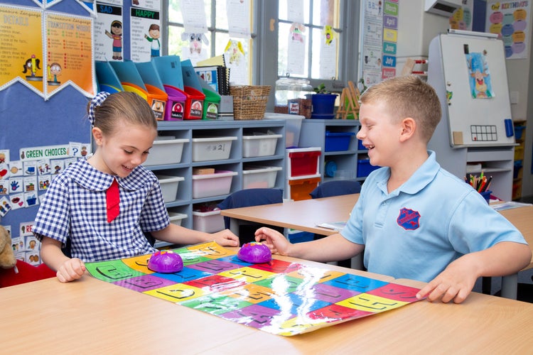 Two students working and smiling in class at a table.