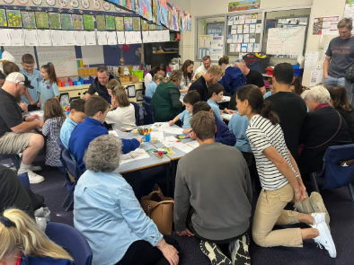 Families and students working at tables in a classroom.