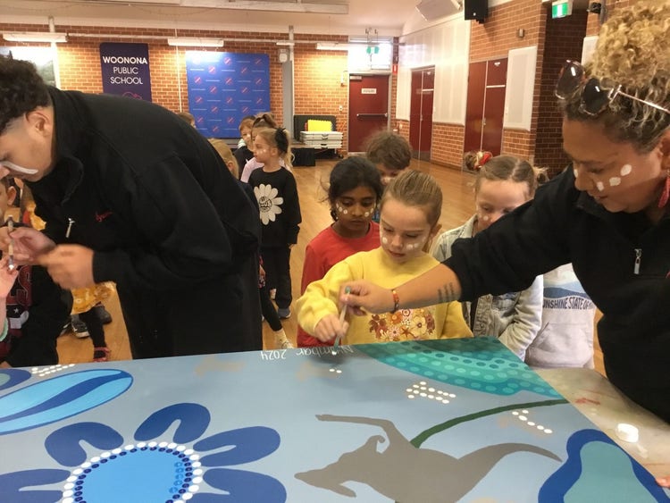 Group of students and teachers working on aboriginal art.